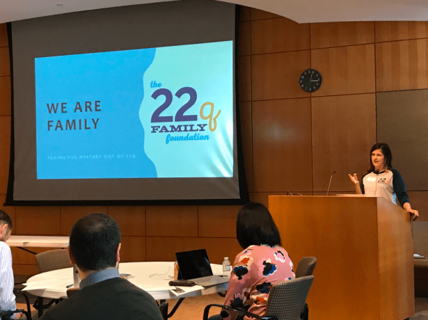 a person standing at a podium with a large screen